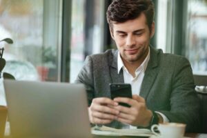 homem jovem mexendo no celular para realizar investimentos internacionais