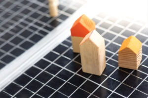 Blocos de montar representando casas sobre painel de energia solar.