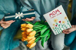 Imagem de várias mãos segurando presentes para as mães, representando lembrança para o Dia das Mães