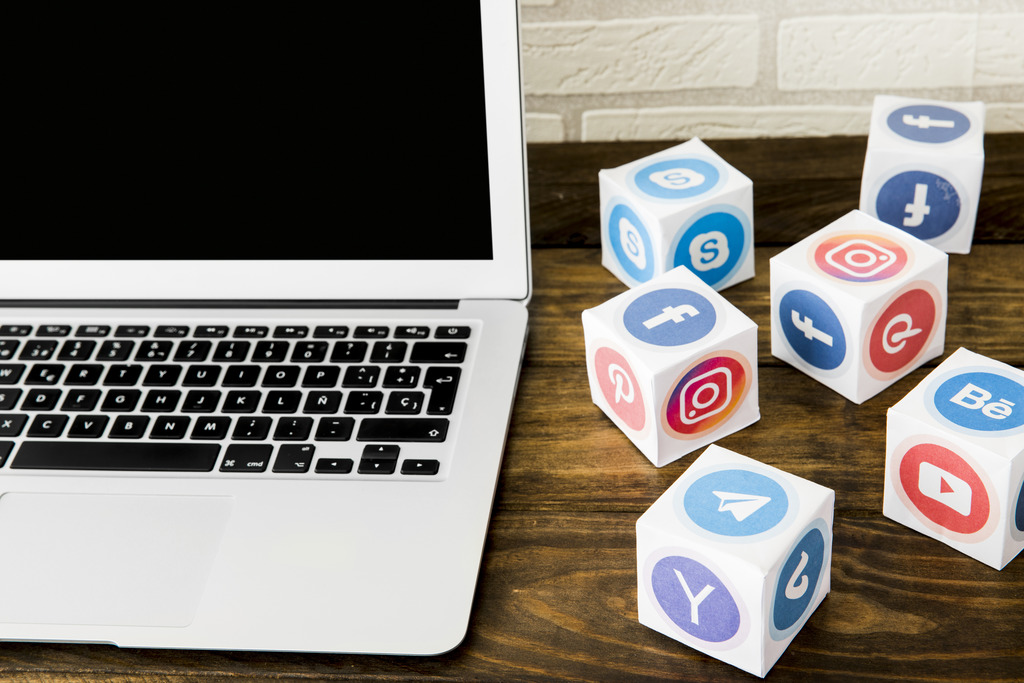 Imagem de um notebook e vários ícones de redes sociais, ilustrando a maior rede social do mundo.