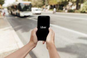 Mãos segurando celular com aplicativo Uber aberto representando a parceria entre Uber e Oracle