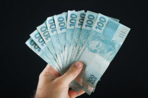 Mão com notas de 100 reais